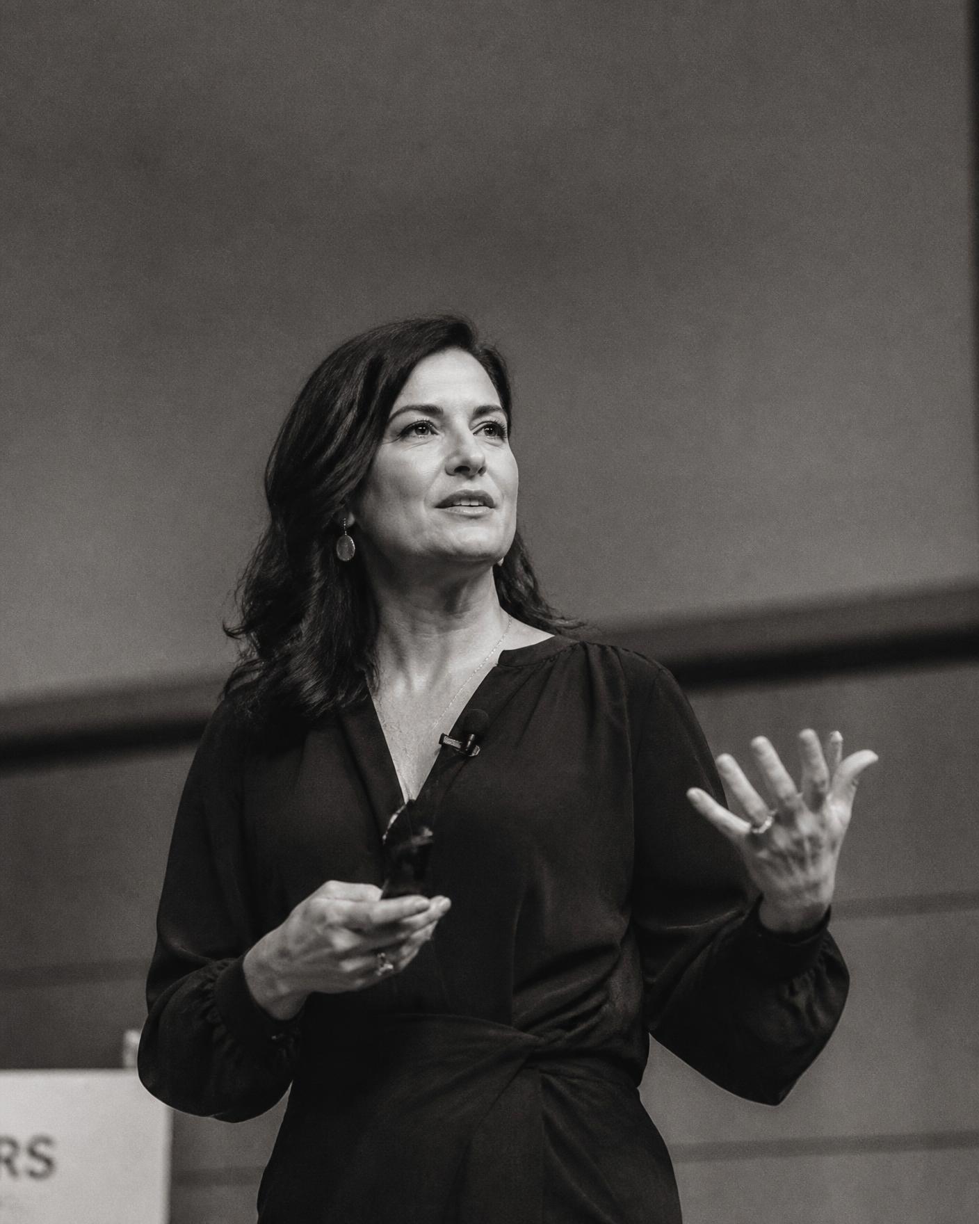 A woman speaker mid-gesture on stage.
